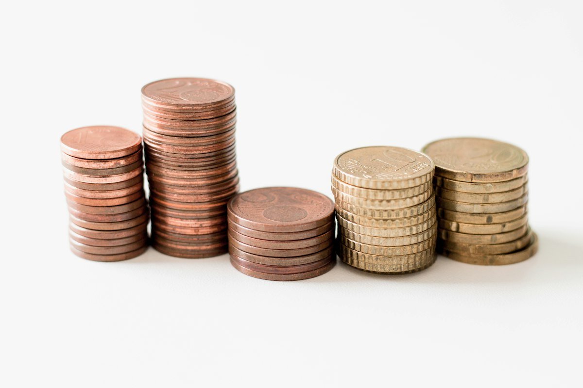 Monedas doradas apiladas sobre una superficie blanca, símbolo del ahorro para imprevistos