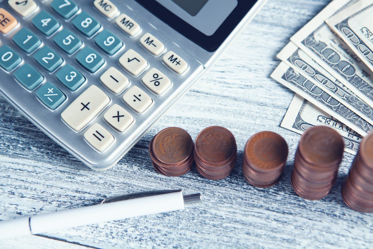 Calculadora, pluma y dinero sobre una mesa para hacer las cuentas de tus deudas