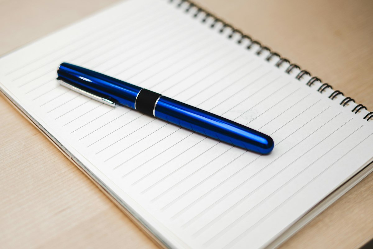 Cuaderno y pluma sobre un escritorio para anotar costos fijos y variables del negocio