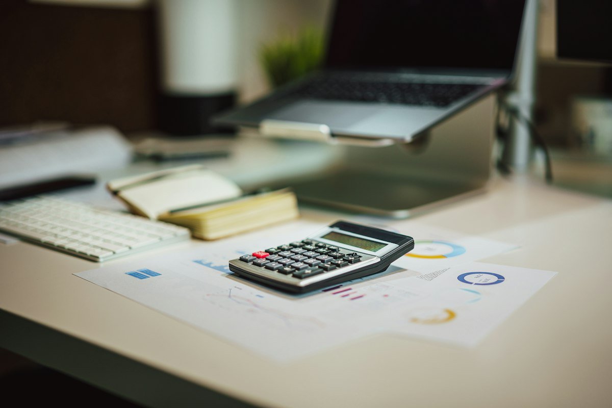 Calculadora sobre una mesa junto a una laptop para llevar el control de comprobantes fiscales