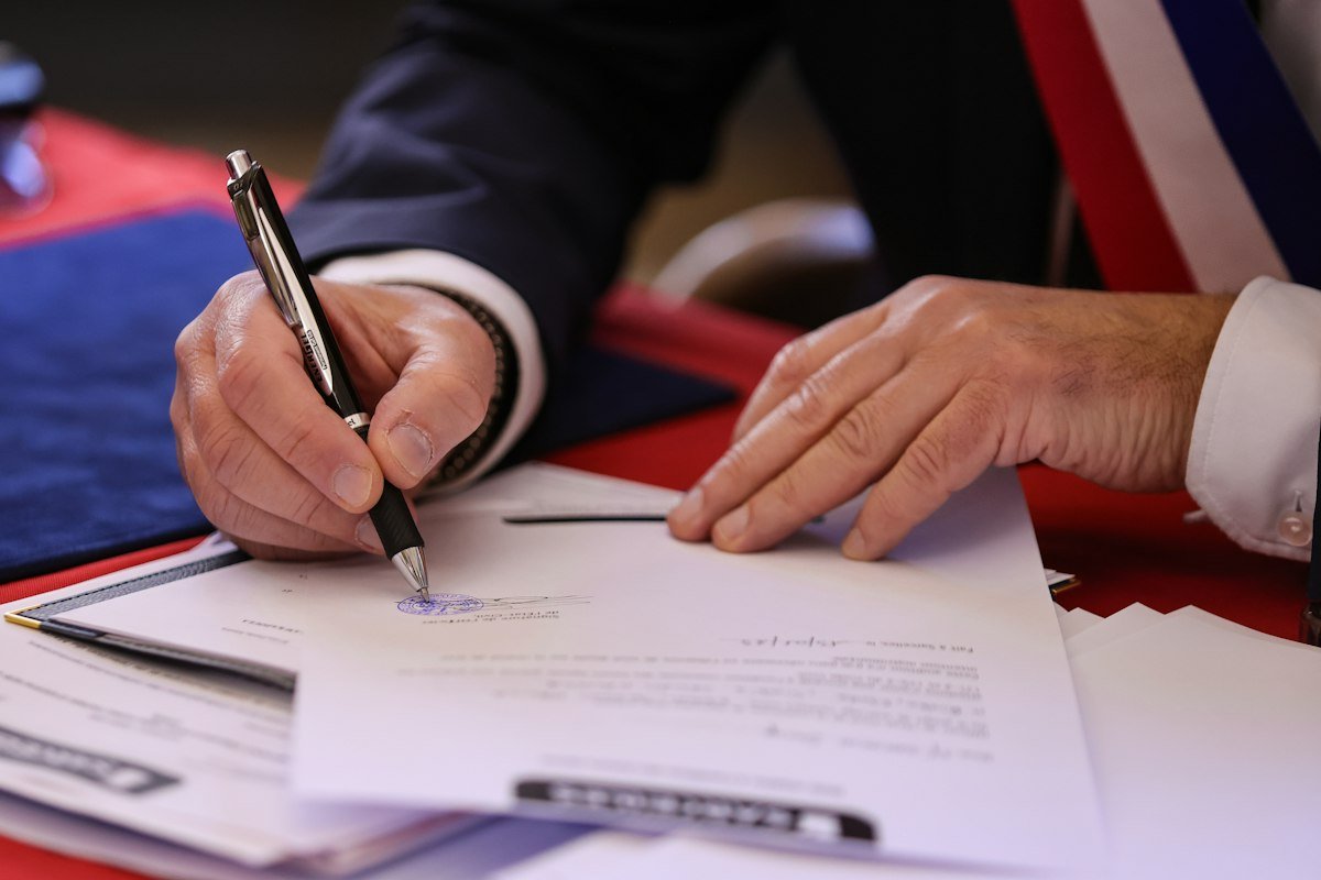 Persona firmando un contrato de crédito con pluma después de revisar el CAT