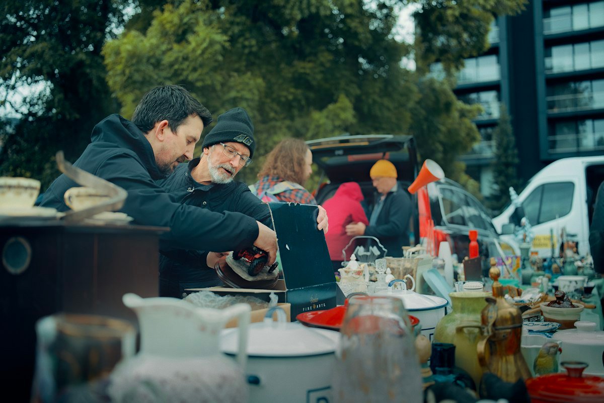 Personas viendo productos en un puesto de mercado al aire libre, donde el precio decide la venta